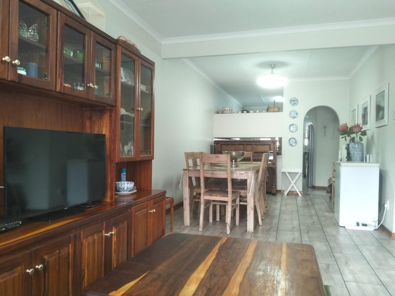 Open plan living and dining area featuring tiled flooring, coved ceilings, and an arched entryway leading to the kitchen space.