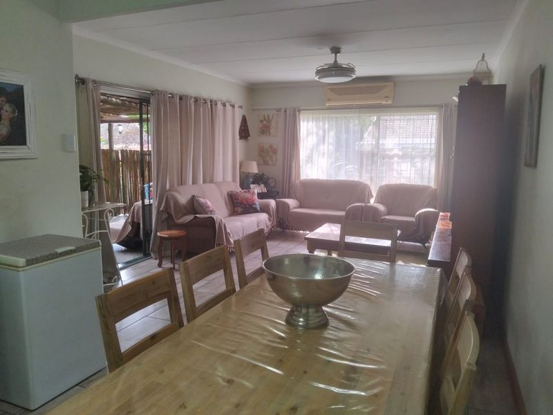 Open-plan living and dining area featuring tiled flooring, a ceiling fan, split-system air conditioning, and sliding glass doors leading to an outdoor space.