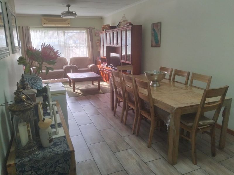 Open-plan living and dining area featuring tiled flooring, a ceiling fan, and a wall-mounted air conditioning unit with access to the exterior.