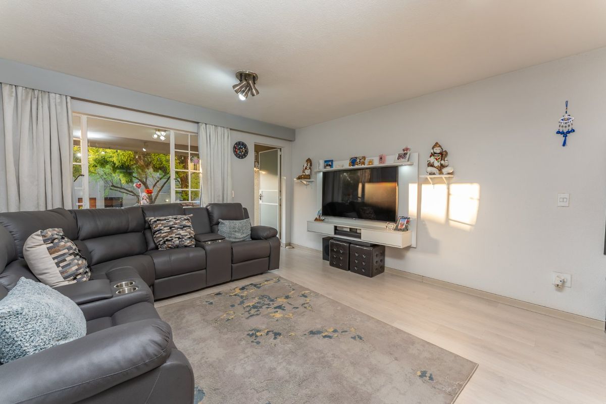 A bright living room featuring light laminate flooring, a built-in media console, and a large sliding glass door providing access to the outdoor area.