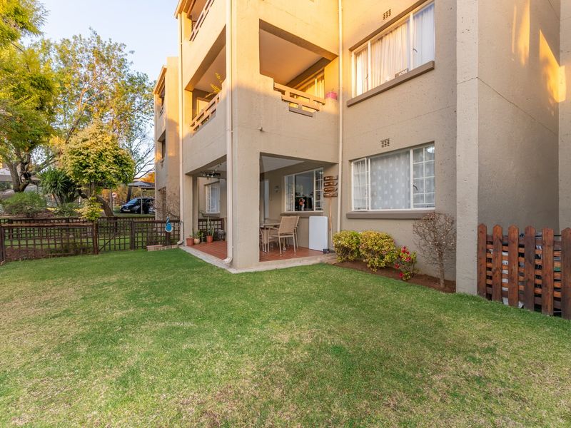 Rear view of the townhouse featuring a covered patio, balcony, and a private garden area with timber fencing.