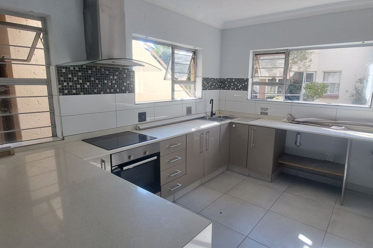 A functional kitchen featuring quartz countertops, built-in oven, electric hob, and tiled splashbacks, currently vacant and ready for final finishing touches.