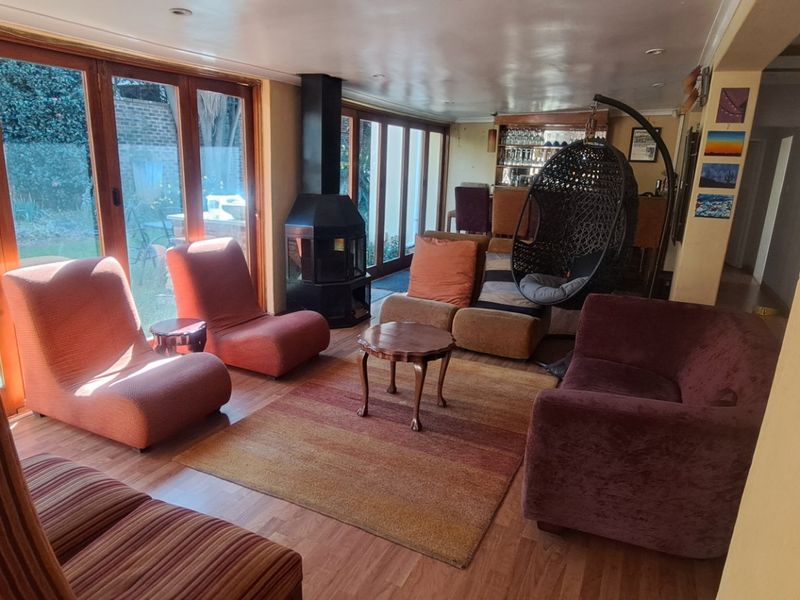 Spacious open-plan living area featuring a freestanding fireplace, laminate flooring, and large wooden folding doors that provide seamless access to the garden.