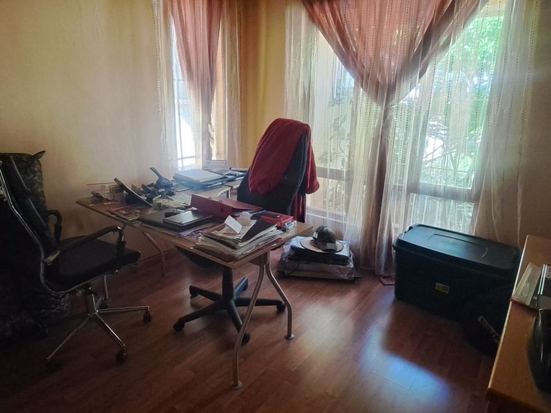 A functional home office space featuring laminate flooring and a large window allowing for natural light.