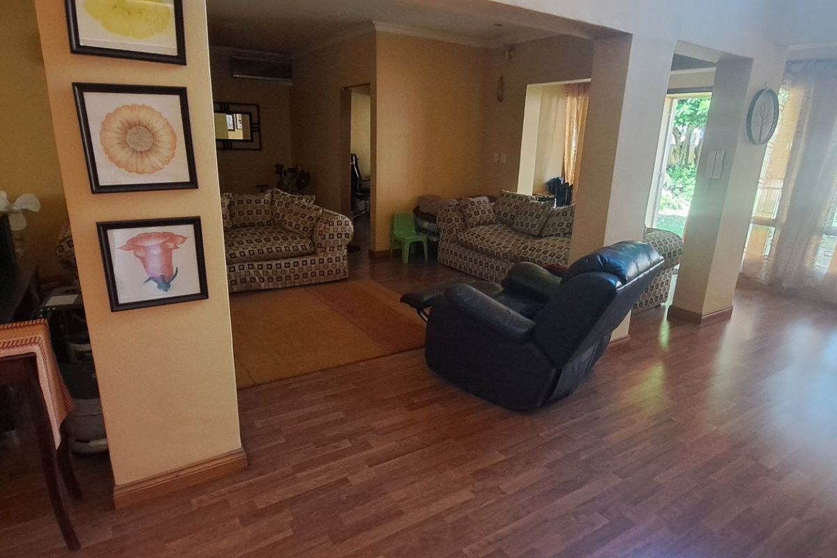 Spacious living area featuring laminate flooring, an air conditioning unit, and large sliding glass doors providing natural light and garden access.