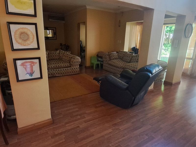 Spacious living area featuring laminate flooring, an air conditioning unit, and large sliding glass doors providing natural light and garden access.