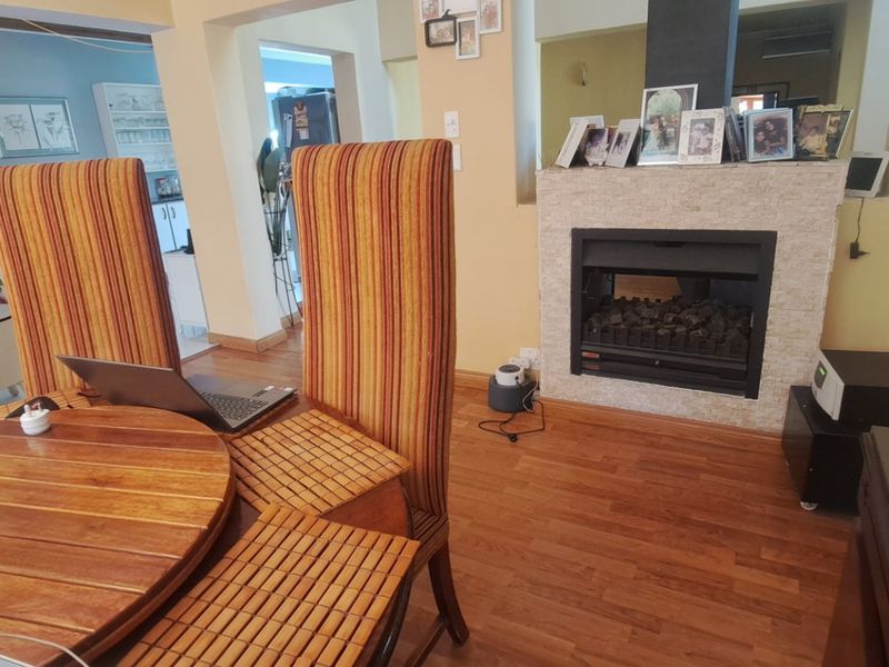 Open plan living area featuring laminate flooring and a built-in fireplace with stone cladding surround.