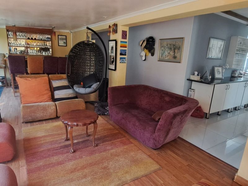 Open-plan living area featuring a fireplace, built-in bar, and adjacent kitchen with tiled and laminate flooring.