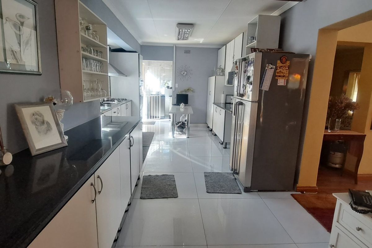A functional kitchen featuring white cabinetry, black granite countertops, and tiled flooring, offering a clean and practical workspace.