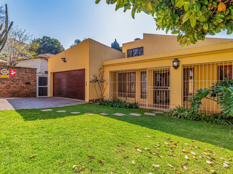 Front exterior view of the house featuring a paved driveway, single garage, manicured lawn, and secure metal security bars on windows and doors.