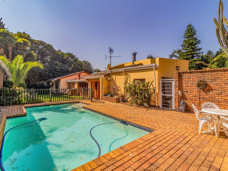 Outdoor pool area featuring brick paving, a perimeter brick wall, and a metal security fence, providing a private space for recreation and relaxation.