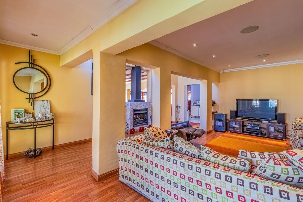 Spacious living room featuring hardwood flooring, recessed lighting, and a central built-in fireplace, offering a warm and inviting atmosphere.