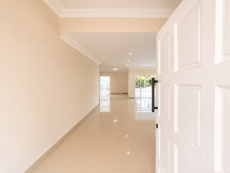 A bright and spacious entrance hall featuring neutral tiled flooring, clean walls, and recessed lighting, leading through to an open-plan living area.