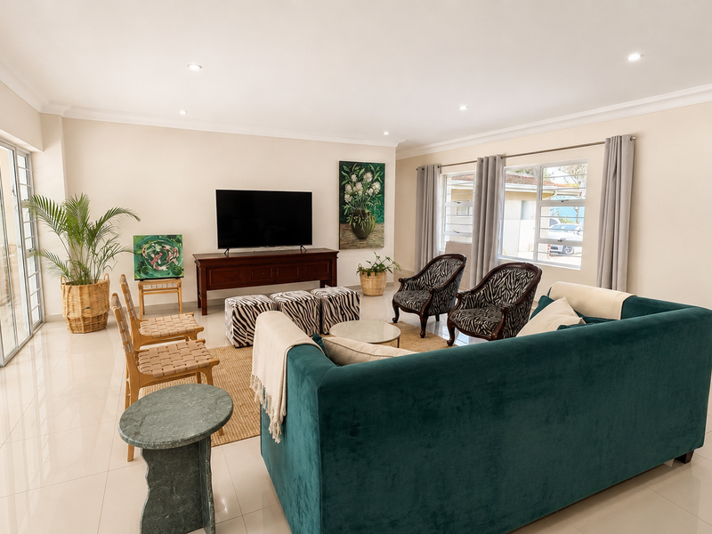 Spacious living room featuring polished tiled flooring, recessed downlighting, and large sliding glass doors providing seamless access to the outdoor patio area.