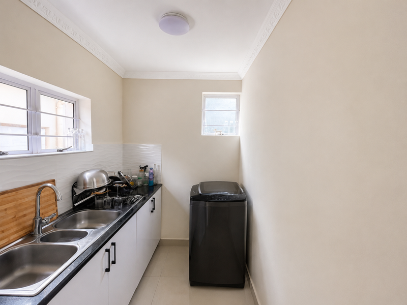 A functional laundry room featuring a double stainless steel sink, laminate countertops, built-in cabinetry, and tiled backsplash.