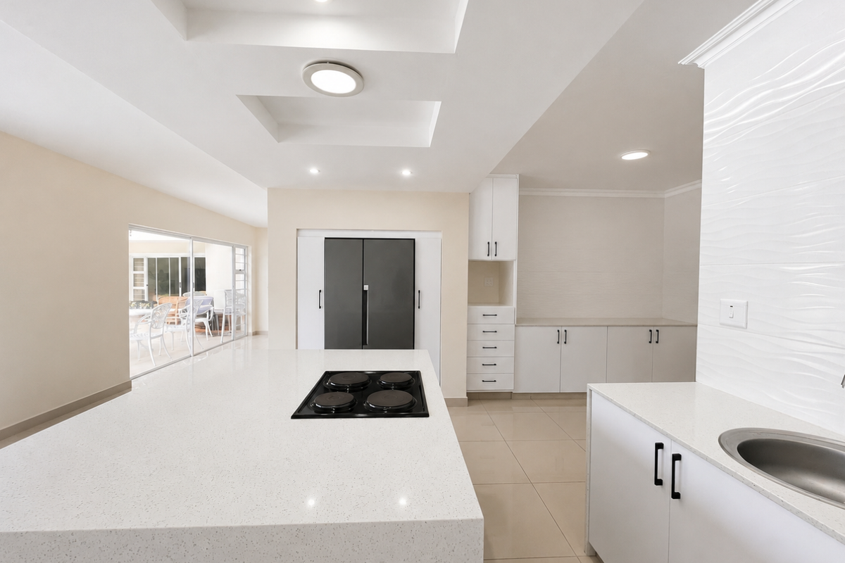 Modern kitchen featuring a large central island with a built-in hob, quartz countertops, ample white cabinetry, and sleek tiled flooring.