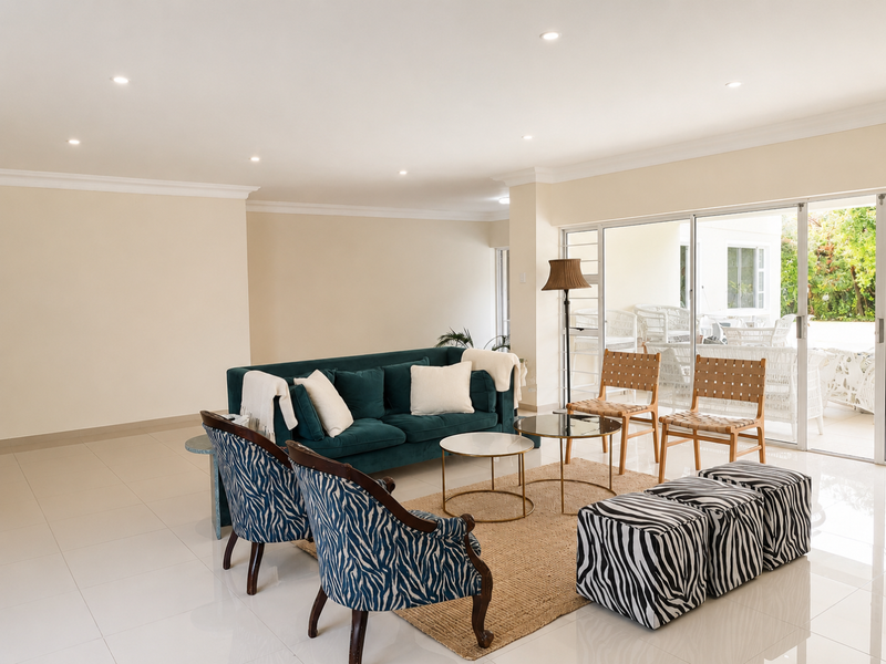 Spacious living area featuring neutral tiled flooring, recessed downlighting, and large sliding glass doors providing seamless access to the outdoor patio.
