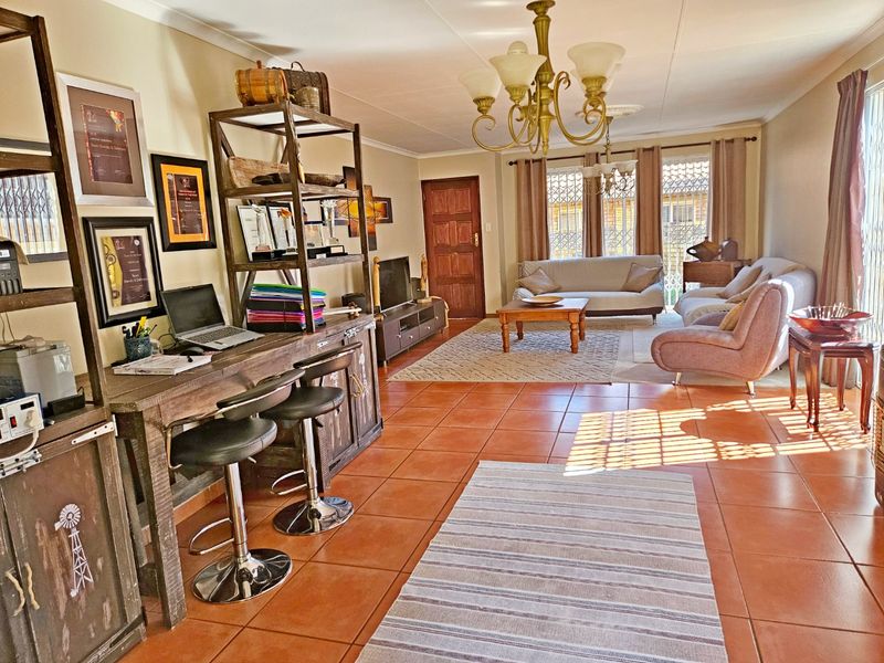 Spacious living area featuring ceramic floor tiles, large sliding glass doors with security gates, and a central chandelier, offering a comfortable and functional layout.