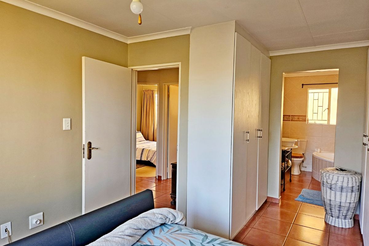 A bedroom featuring built-in cupboards, tiled flooring, a ceiling fan, and direct access to an en-suite bathroom.