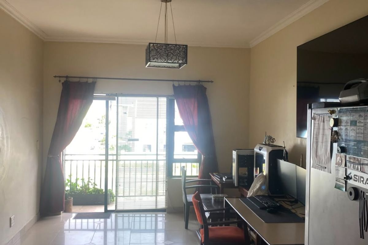 A living room featuring tiled flooring, a pendant light fixture, and a sliding glass door providing access to a balcony.