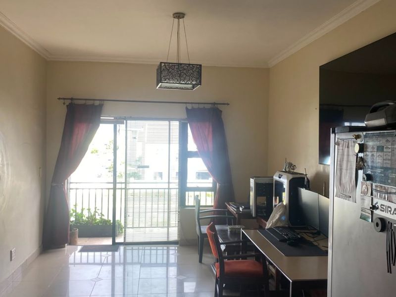 A living room featuring tiled flooring, a pendant light fixture, and a sliding glass door providing access to a balcony.