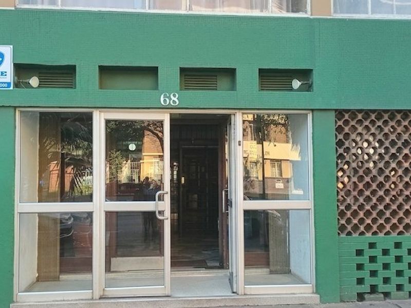 The front entrance of the apartment building features a glass door with aluminium framing and decorative breeze block wall detailing.