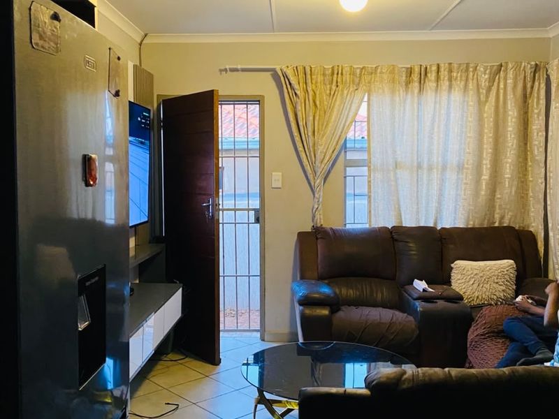 Open plan living area featuring tiled flooring, a security gate at the entrance, and direct access to the exterior.