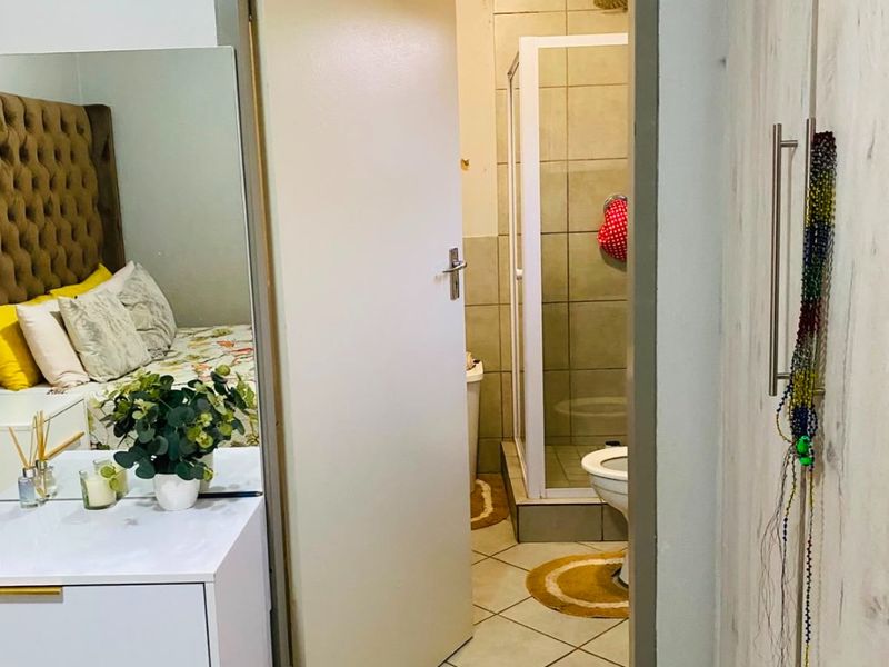 Bedroom featuring built-in wardrobe storage and direct access to an en-suite bathroom with a shower and tiled finishes.