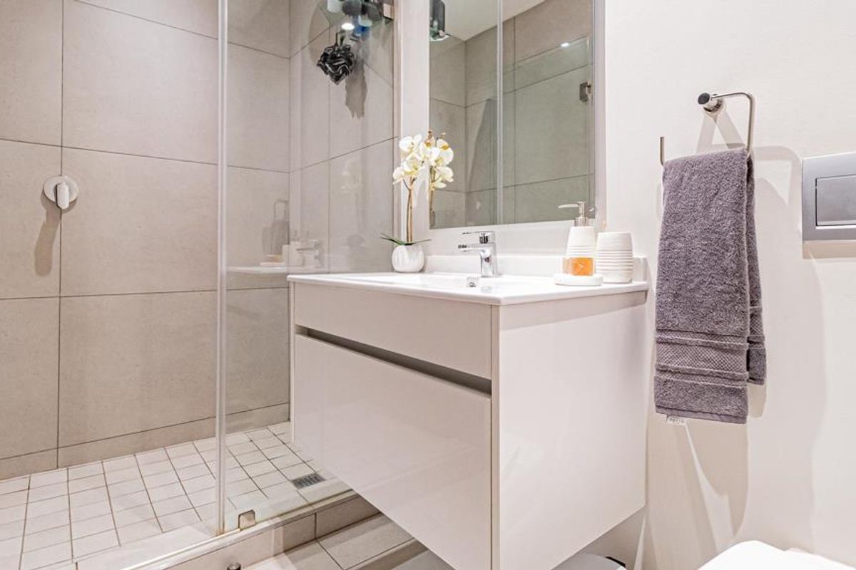 Modern bathroom featuring a wall-mounted vanity, glass-enclosed shower with tiled finishes, and contemporary fixtures.