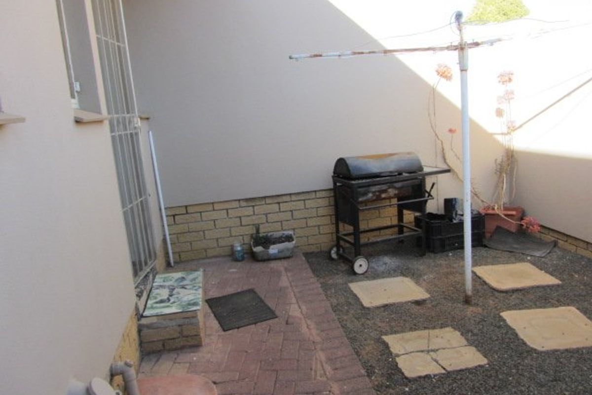 A compact rear courtyard featuring brick paving, a perimeter brick wall, and a fixed washing line, offering potential for outdoor improvement.