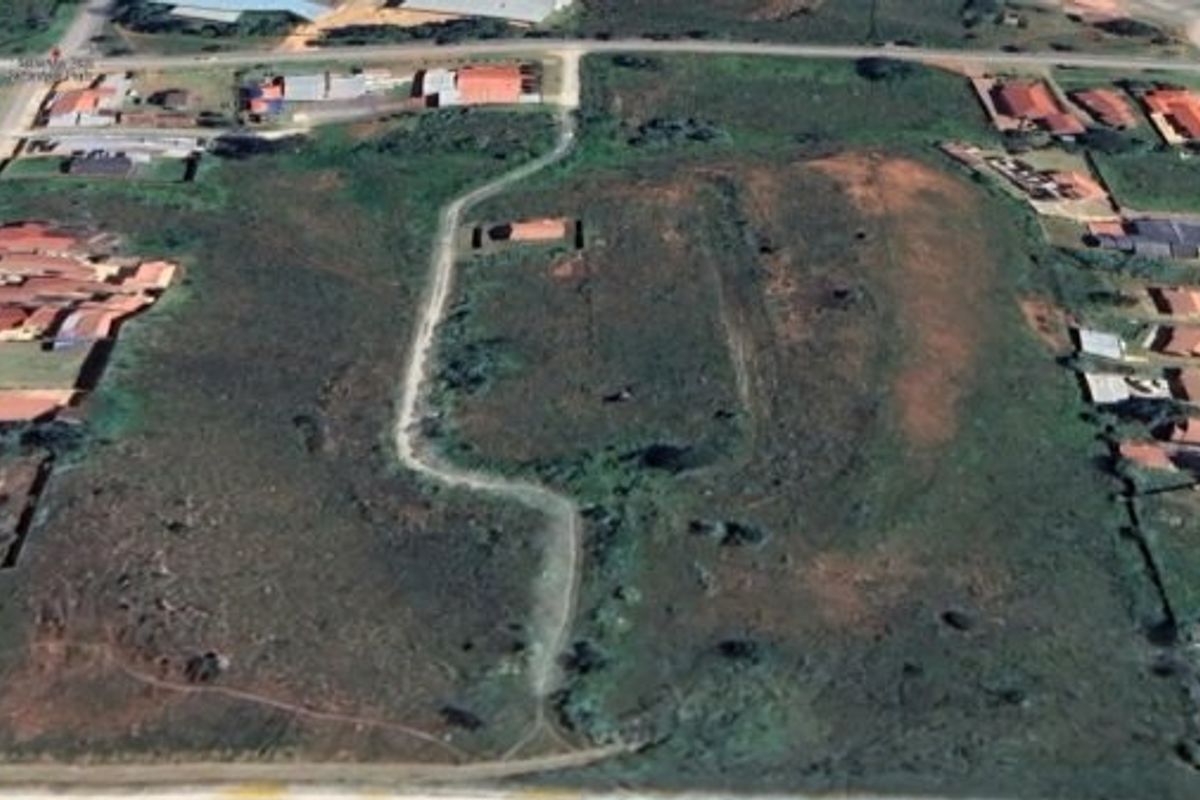 Aerial view of a large vacant residential plot situated within an established suburban neighborhood.