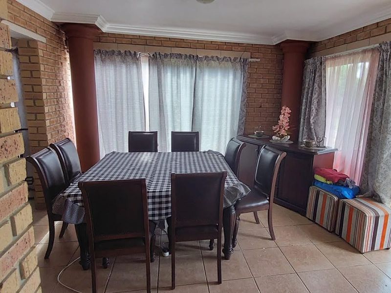 Dining room featuring exposed brick walls, ceramic tile flooring, and large sliding glass doors providing natural light and access to the outdoor area.