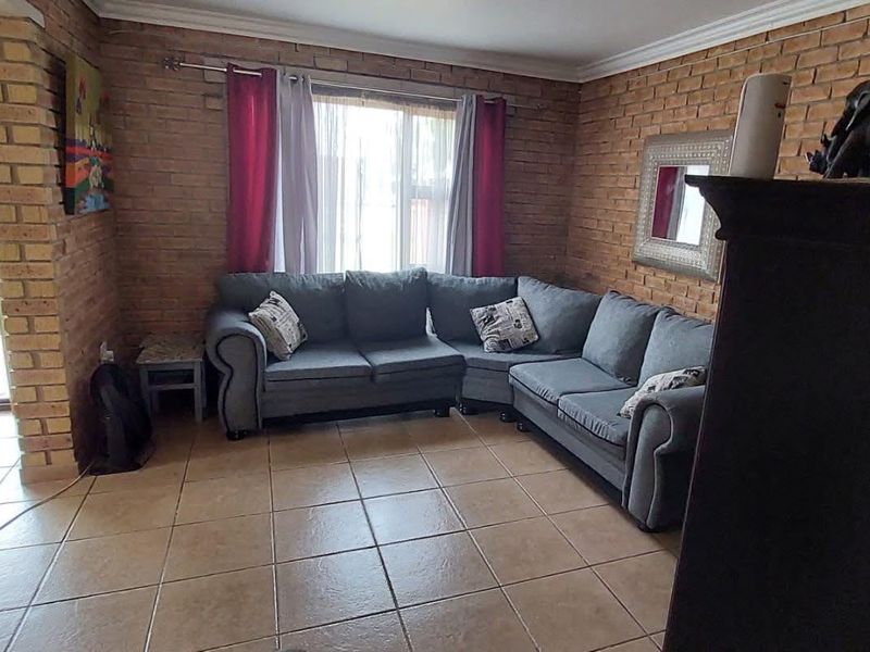 A living room featuring exposed brick walls, tiled flooring, and a sliding glass door providing access to the outdoor area.