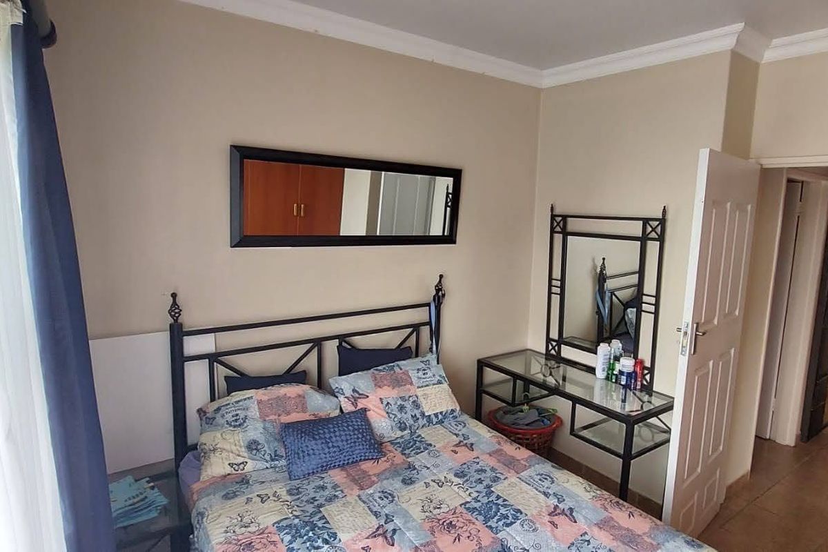 A functional bedroom featuring tiled flooring, crown molding, and a standard panel door, providing a neutral base for personalization.