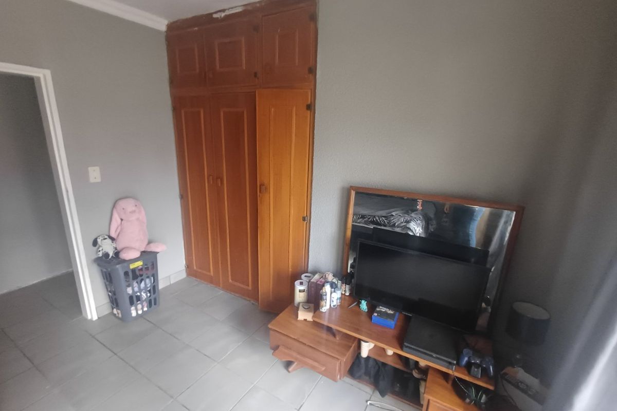 A bedroom featuring built-in wooden cupboards and tiled flooring, requiring cosmetic updates to improve the overall aesthetic and finish.