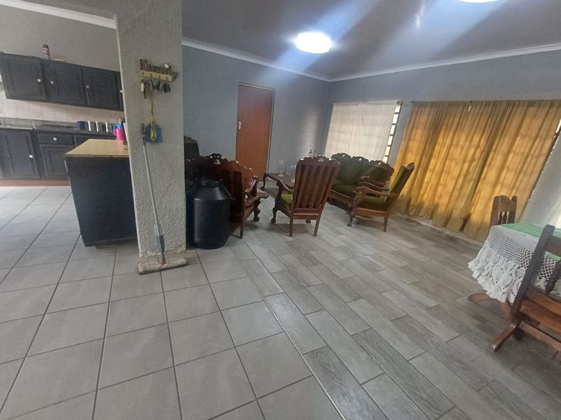 Open plan living and kitchen area featuring tiled flooring, dark kitchen cabinetry, and neutral wall finishes.