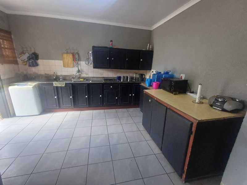 A functional kitchen featuring dark built-in cabinetry, tiled flooring, and a tiled backsplash, offering a practical layout with ample counter space.