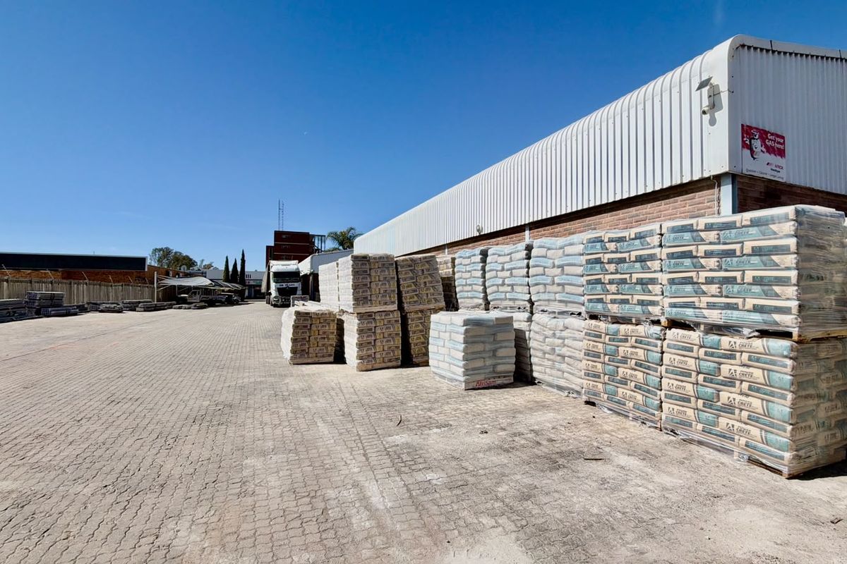 Commercial exterior yard space featuring paved ground, brick and metal cladding construction, and secure perimeter fencing.