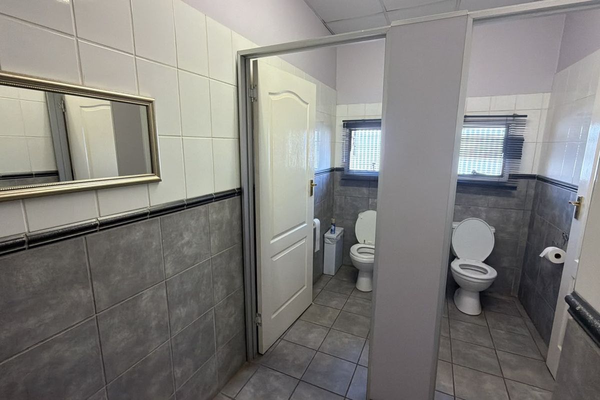 A commercial bathroom facility featuring tiled walls, tiled flooring, and multiple toilet stalls with partition walls.