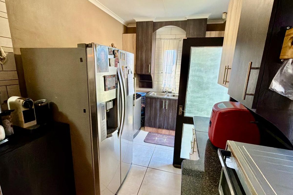 A functional kitchen featuring dark wood-look cabinetry, tiled flooring, and a rear access door leading to the exterior.