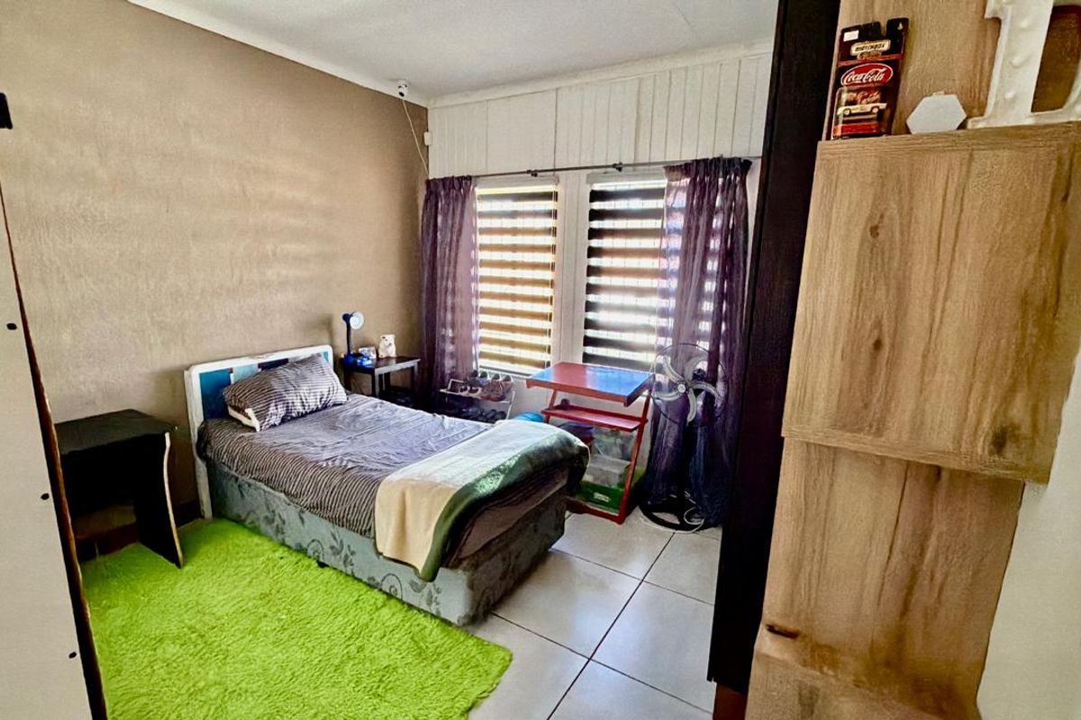 A functional bedroom featuring tiled flooring and dual window blinds, offering a neutral base for personalization.