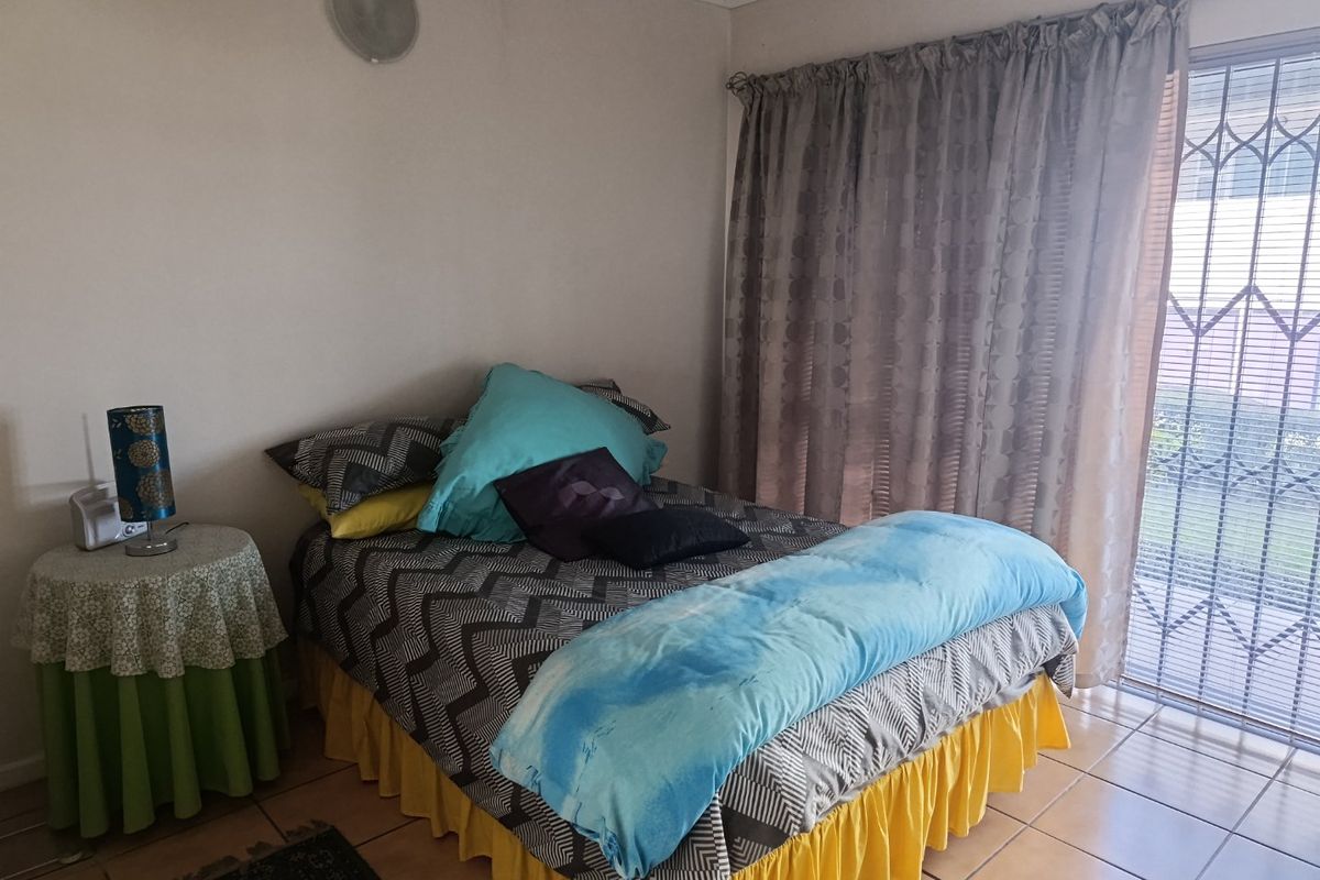 A bedroom featuring tiled flooring and a sliding glass door with an integrated security gate, providing access to the exterior.