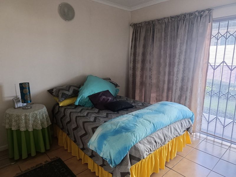 A bedroom featuring tiled flooring and a sliding glass door with an integrated security gate, providing access to the exterior.