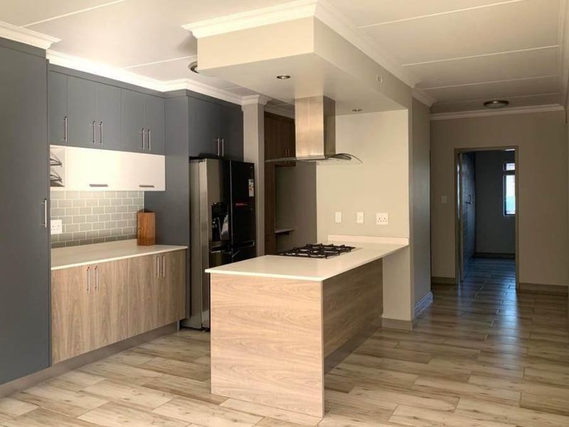 Modern kitchen featuring two-tone cabinetry, stone countertops, a gas hob with extractor fan, and stylish subway tile backsplash with wood-look tiled flooring.