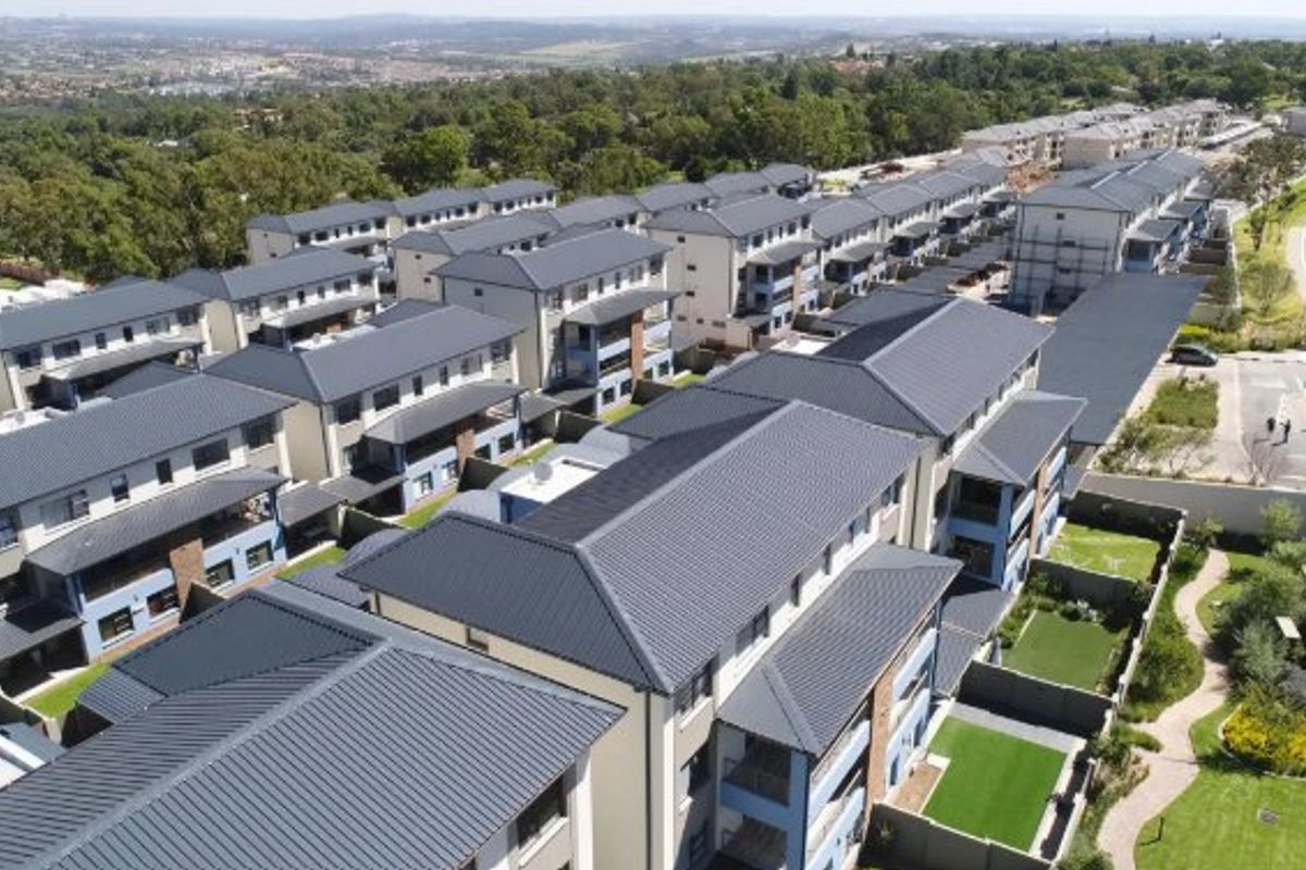Aerial view of a modern apartment complex featuring multiple residential blocks with pitched roofs, private balconies, and landscaped communal garden areas.