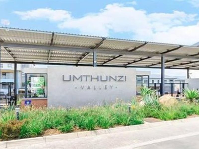 The main entrance to Umthunzi Valley featuring a secure gated access point, covered parking structures, and well-maintained landscaped gardens.