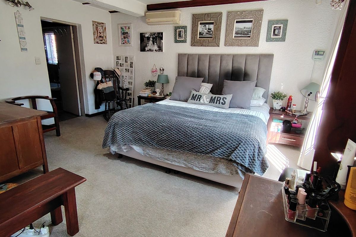 A spacious bedroom featuring carpeted flooring and a wall-mounted air conditioning unit, providing a comfortable and functional living space.