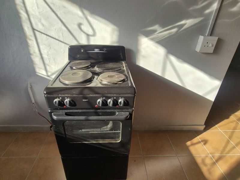 A kitchen area featuring a standalone electric stove on tiled flooring with visible electrical wiring.
