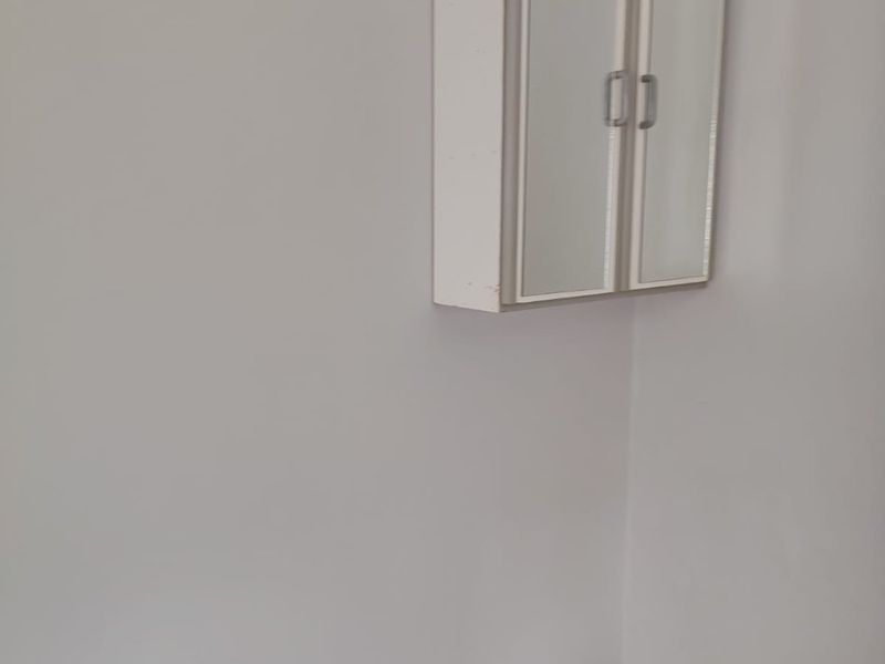 A clean, empty utility space featuring tiled flooring, a wall-mounted storage cabinet, and a ceiling ventilation vent.