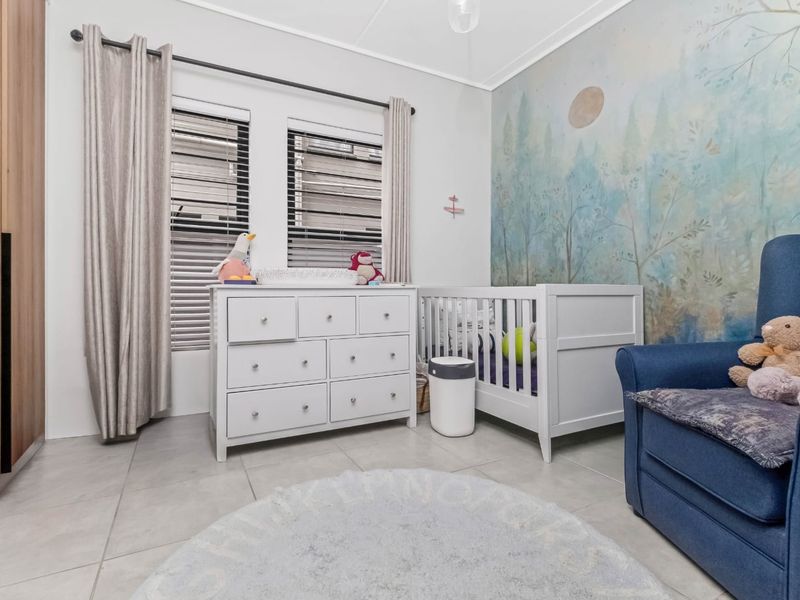 A well-maintained bedroom featuring tiled flooring, built-in wardrobe storage, and venetian blinds, finished with a decorative mural wall.